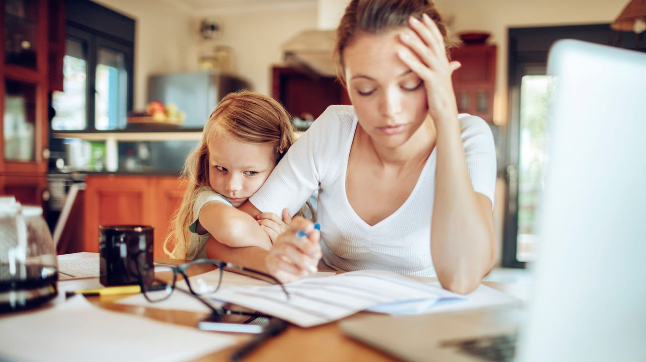 A woman and a child sitting at a table with a laptop.