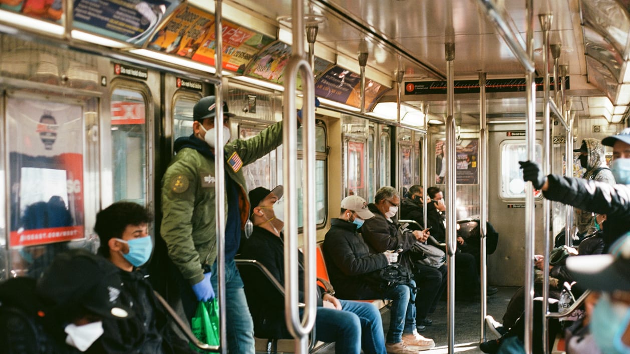 A group of people wearing face masks on a subway train.