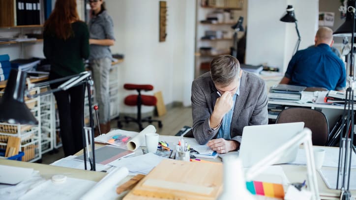 A group of people sitting at a desk in an office.