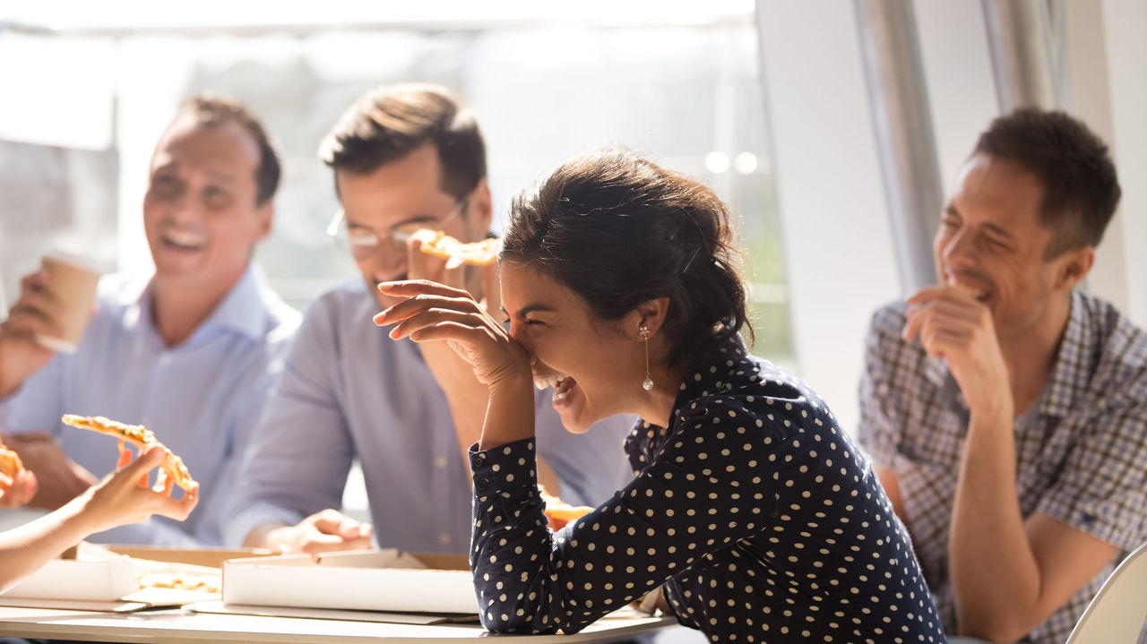 A group of people sitting around a table eating pizza.