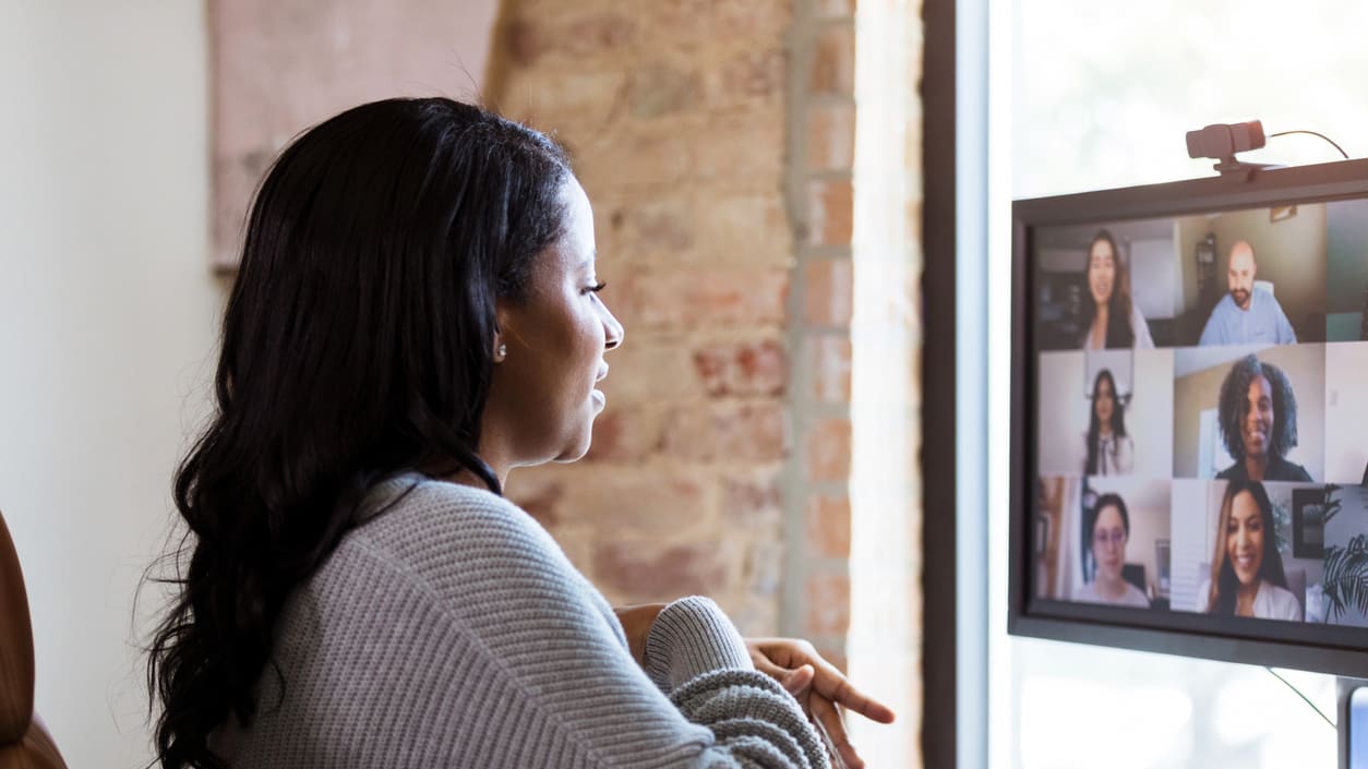 A woman is looking at a computer screen with a group of people on it.