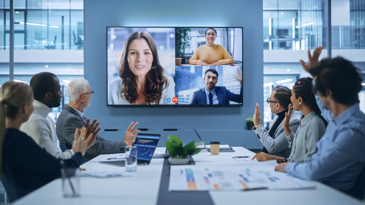 A group of people in a conference room watching a video conference.