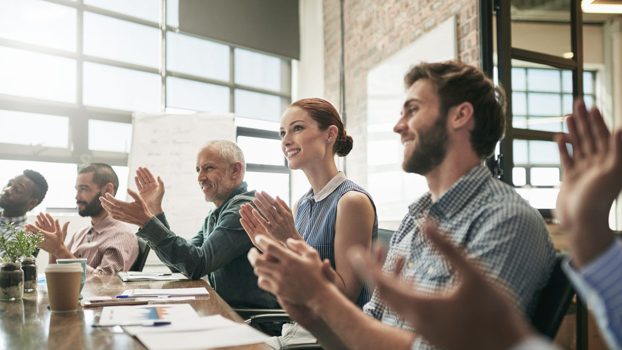 A group of people clapping at a conference table.