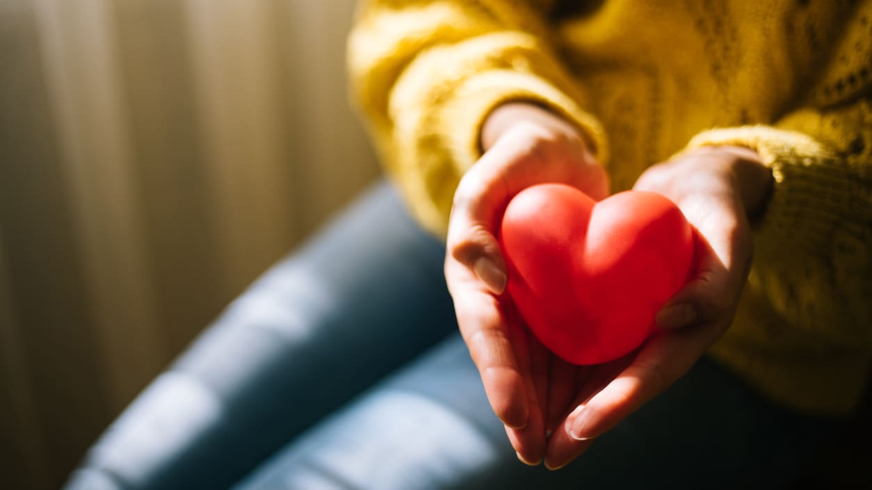 A woman is holding a red heart in her hands.