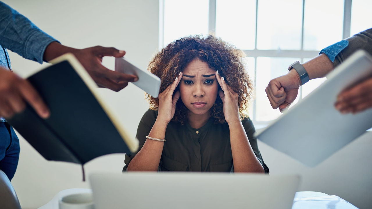 A woman is holding her head up while a group of people are around her.