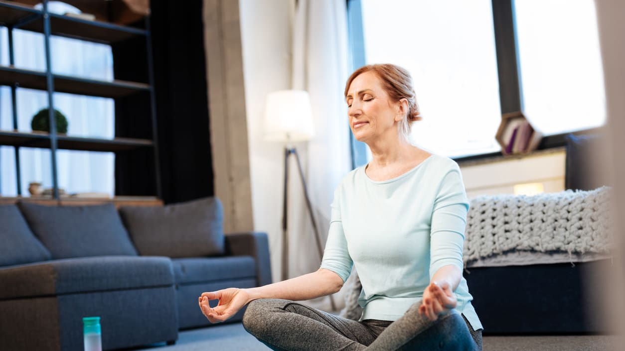 A woman meditating in her living room.
