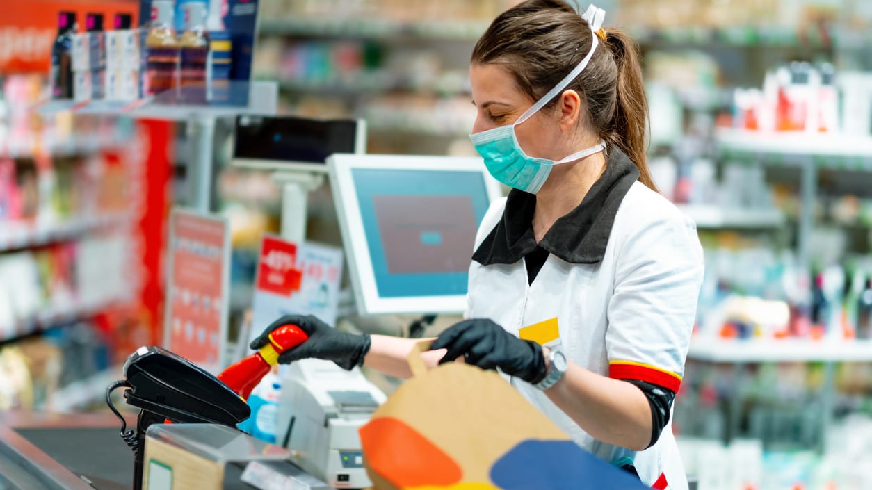 A woman wearing a mask and gloves at a pharmacy.
