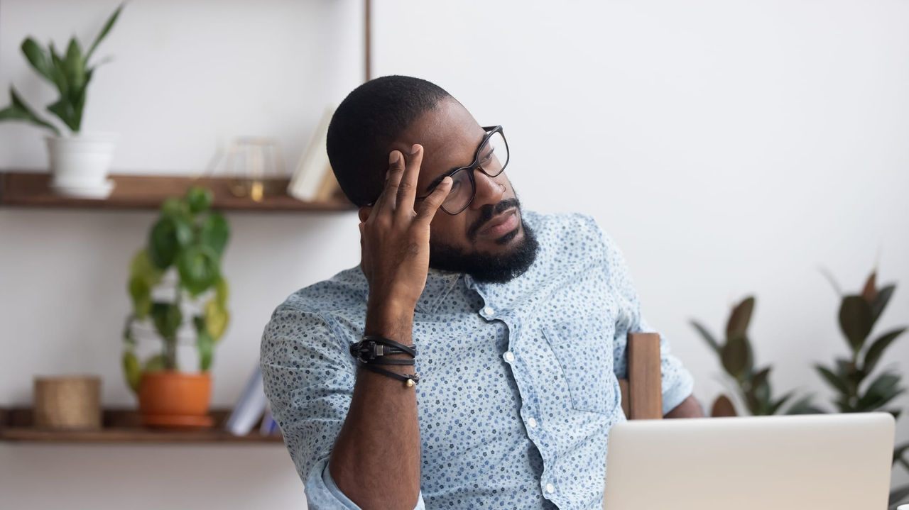 A man sitting at a desk with his hands on his head.