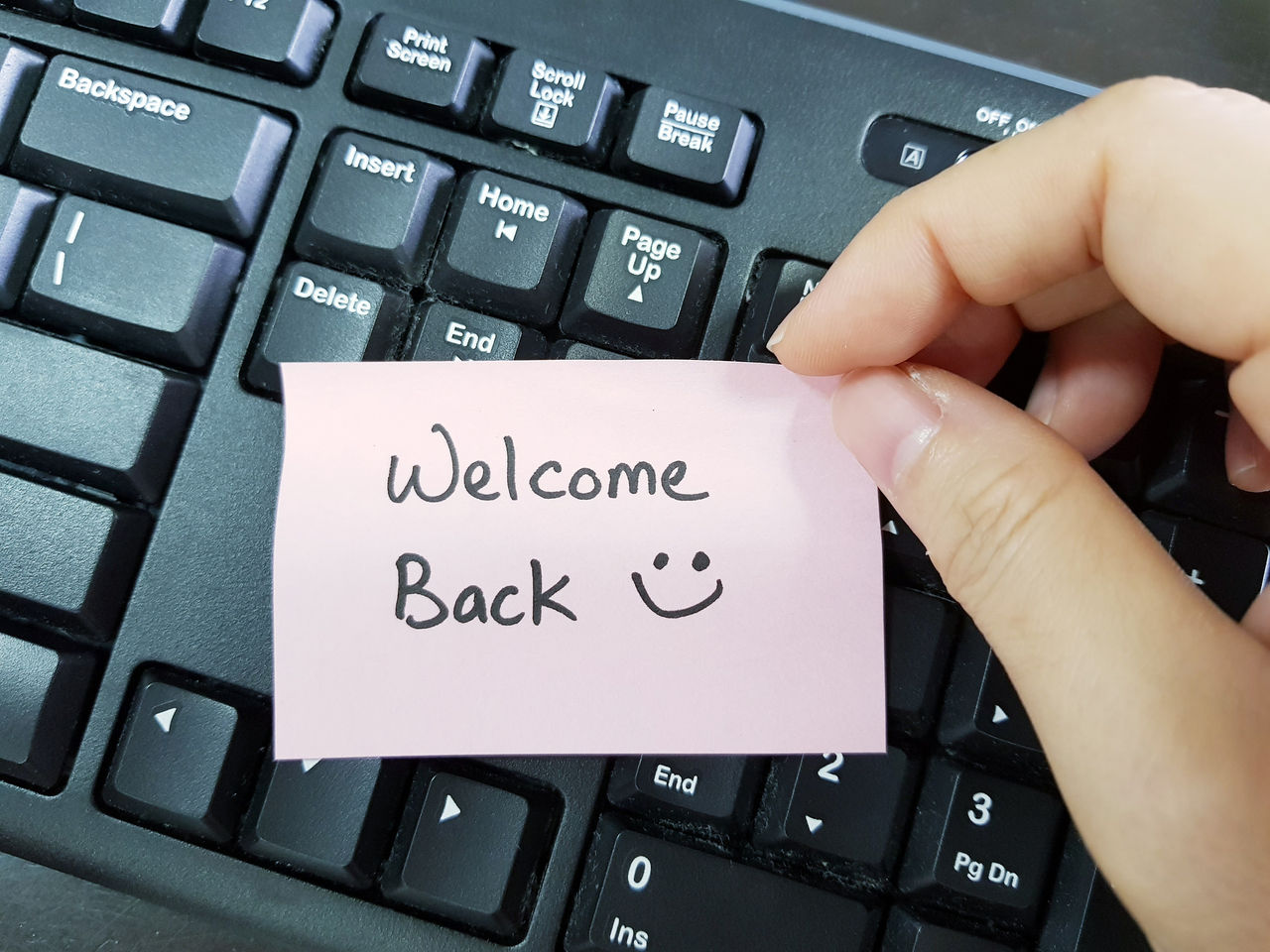 Hand at keyboard with welcome back note