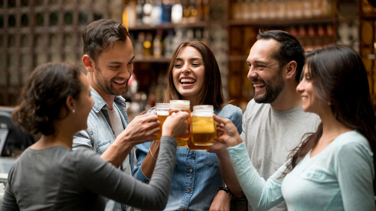 A group of friends toasting beer in a bar.