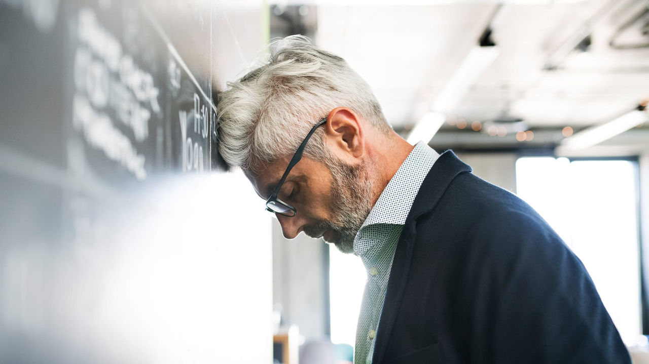 A man leaning against a blackboard in an office.