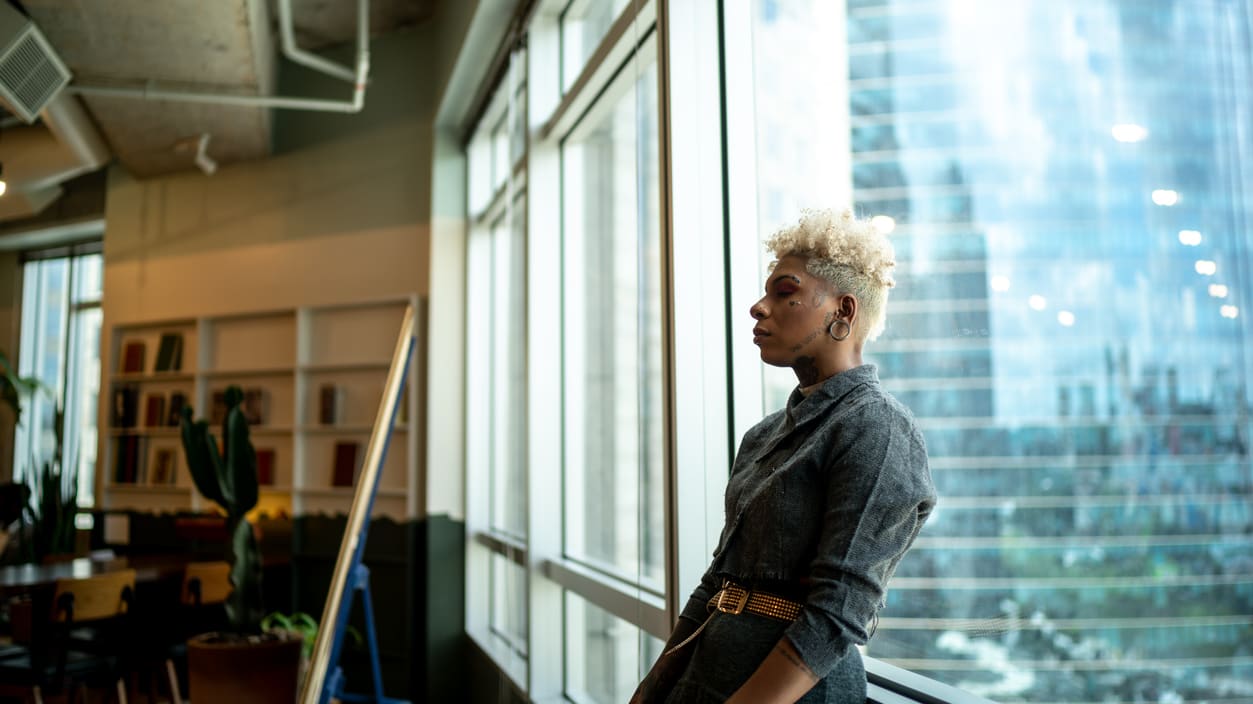 A woman looking out of a window in an office.
