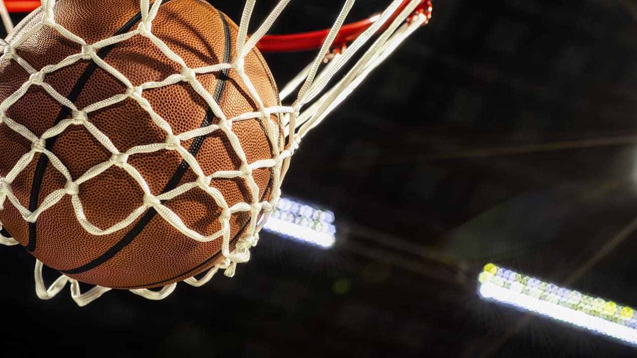 A basketball is going into the hoop of a basketball hoop.