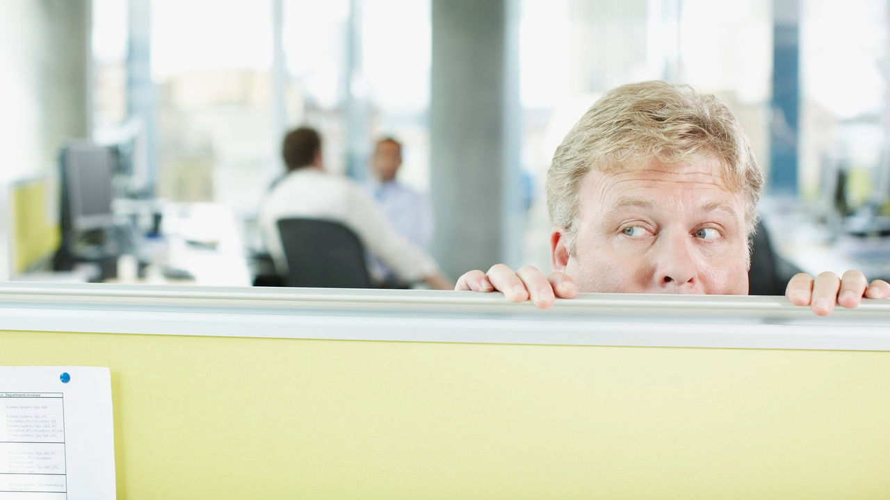 A man peeking over a desk in an office.