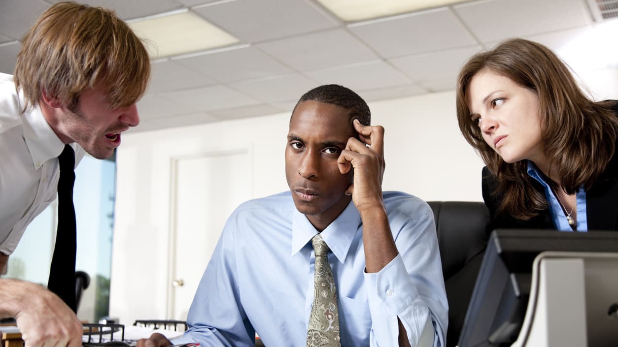 A group of people sitting at a desk in an office.