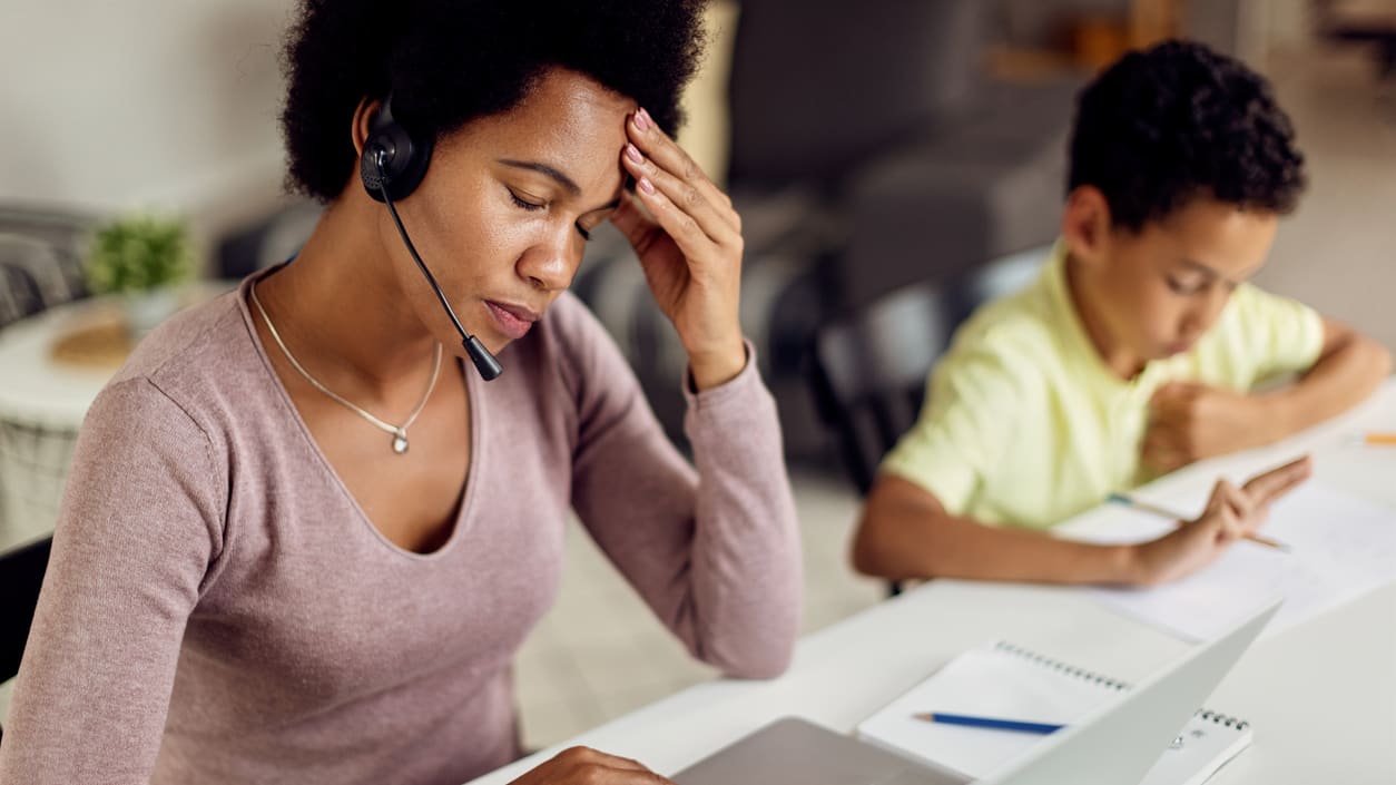 A woman wearing a headset while working on a laptop.