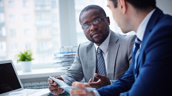 Two businessmen talking at a table in an office.