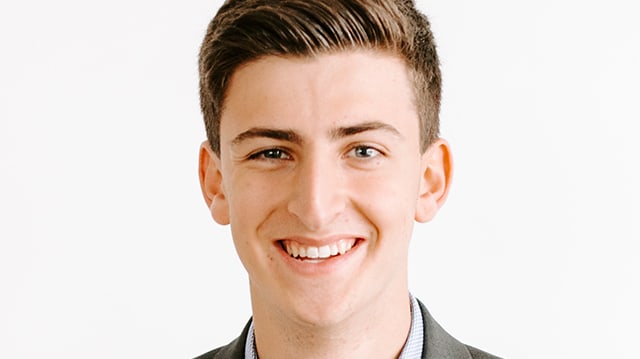 A young man in a suit smiling for the camera.