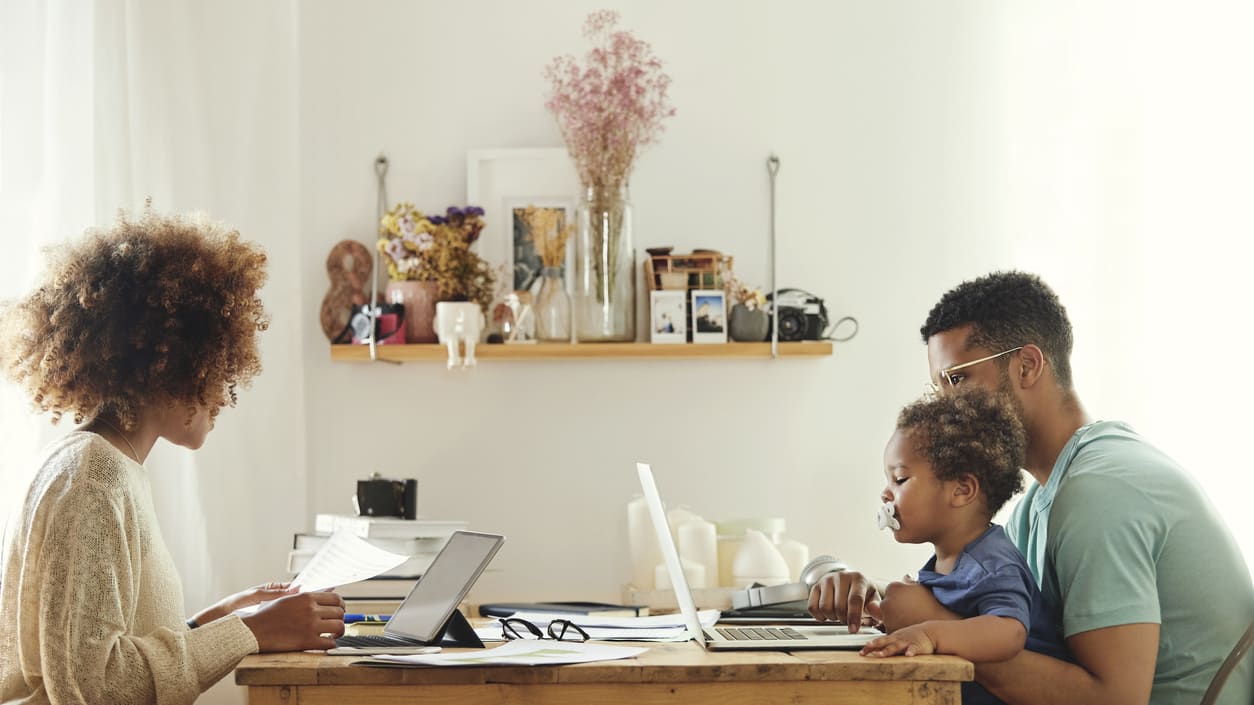 A family sitting at a table working on their laptops.