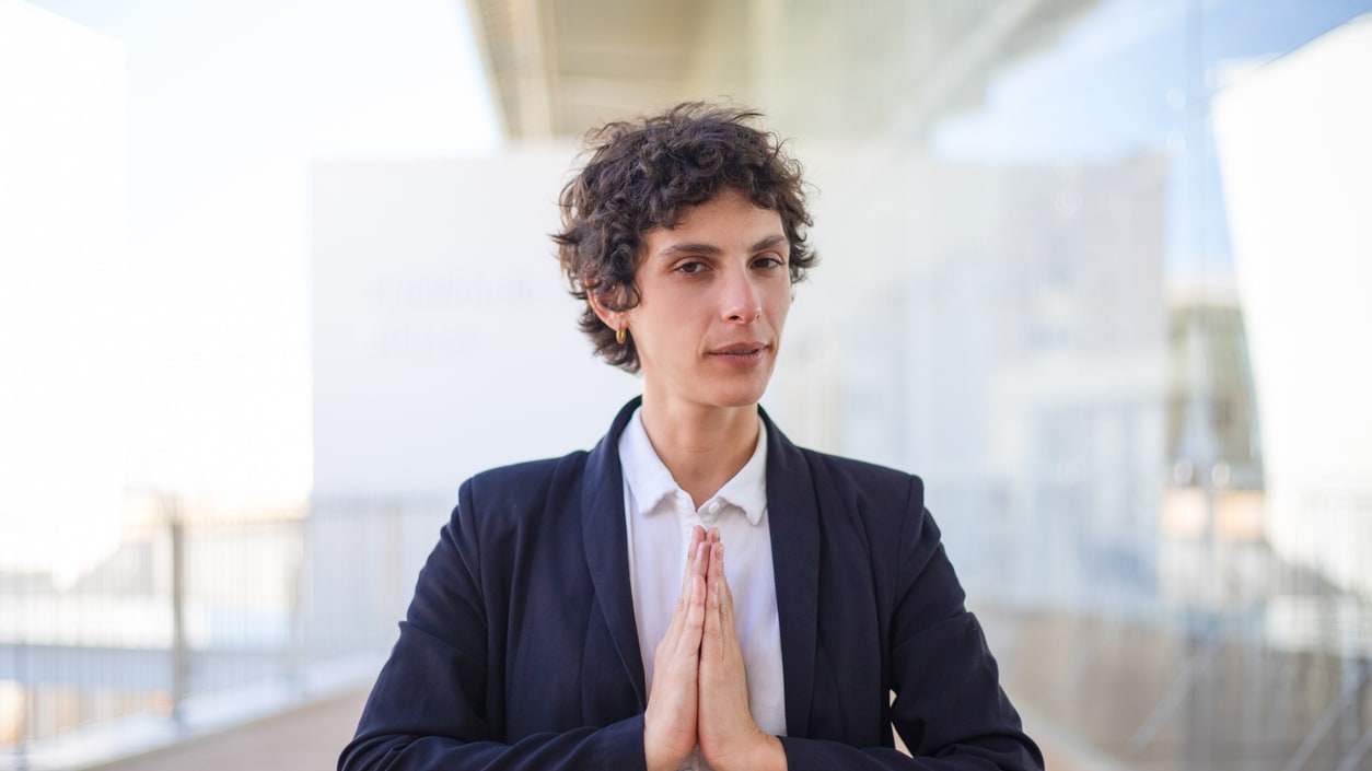 A business woman is meditating in front of a building.