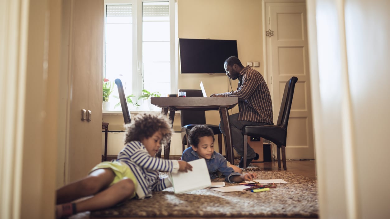 A family of four sitting on the floor in front of a door.