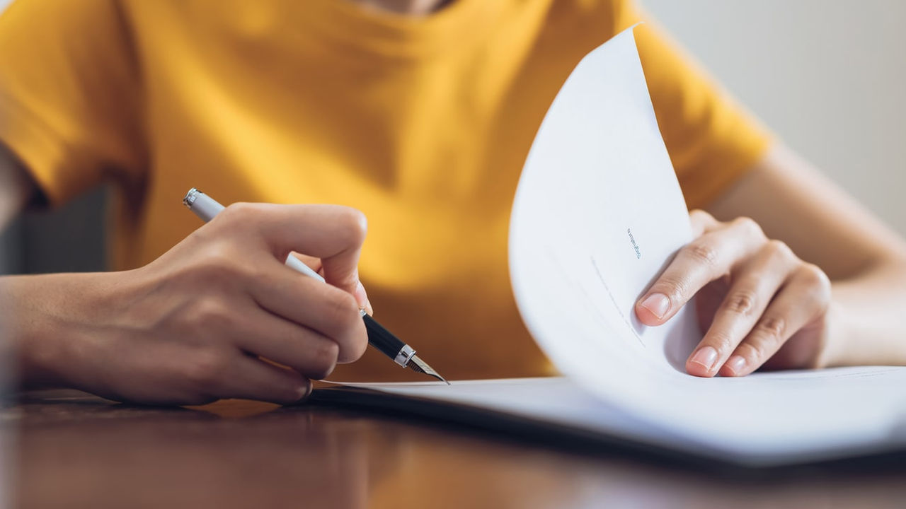 A woman signing a document at a desk.