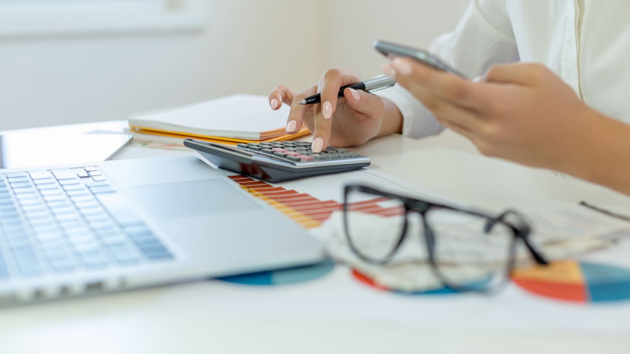 A woman using a calculator on a desk.