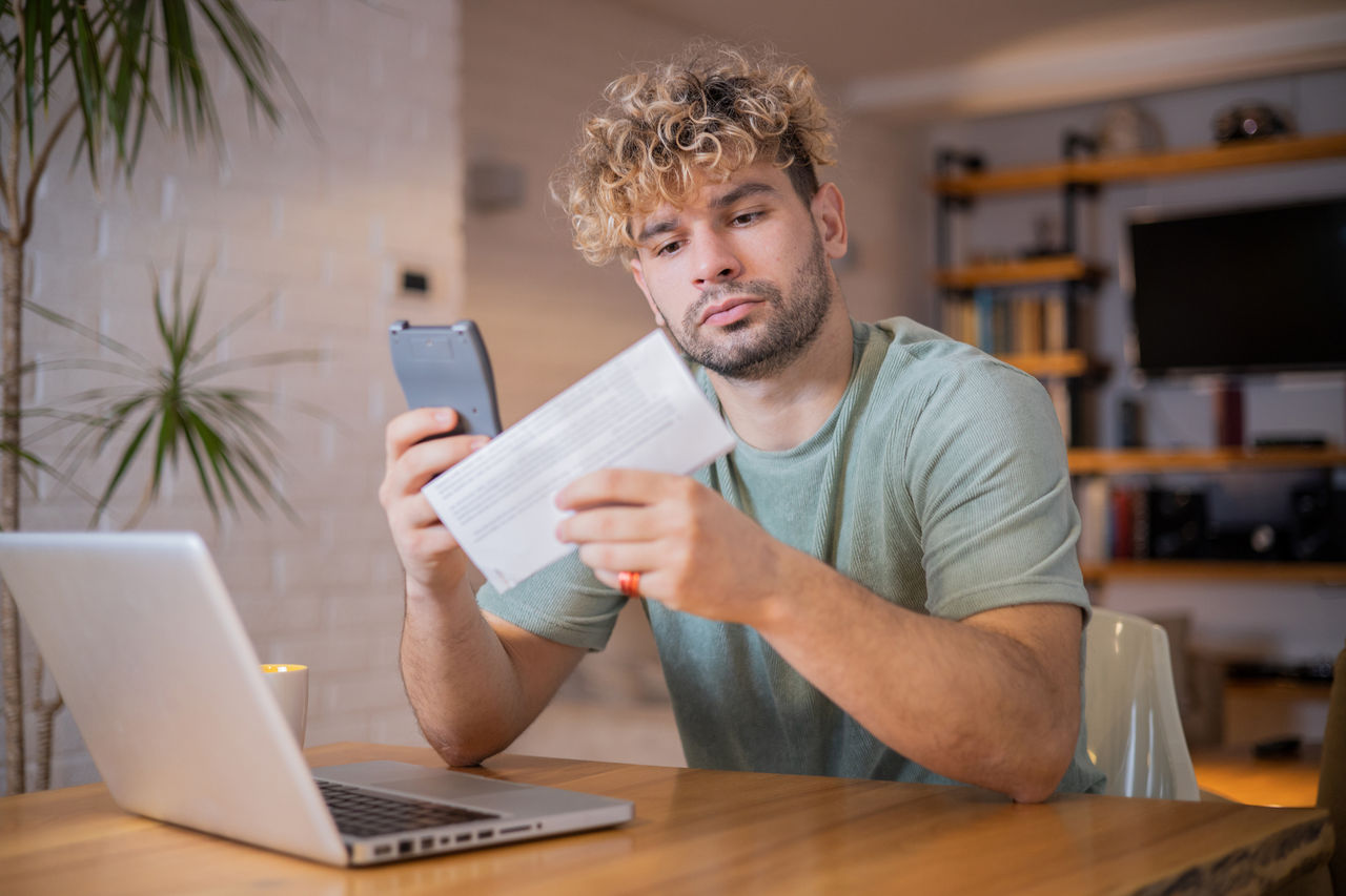 Man with laptop looking at check