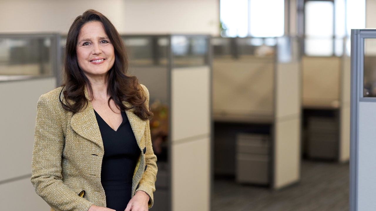 A woman standing in an office cubicle.