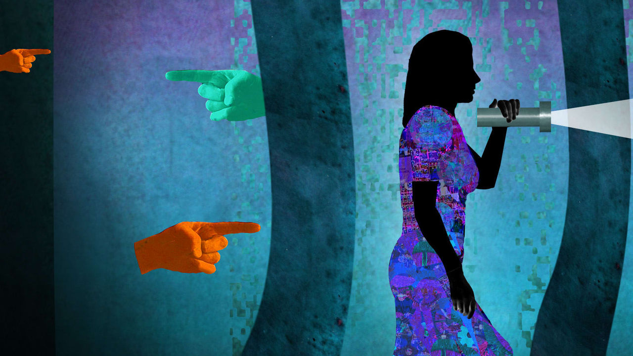 A woman is holding a flashlight in front of a colorful wall.