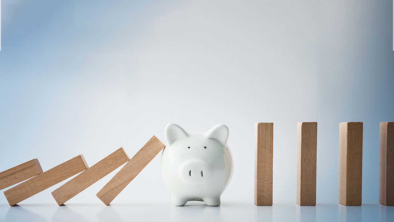 A piggy bank is standing next to a stack of wooden blocks.