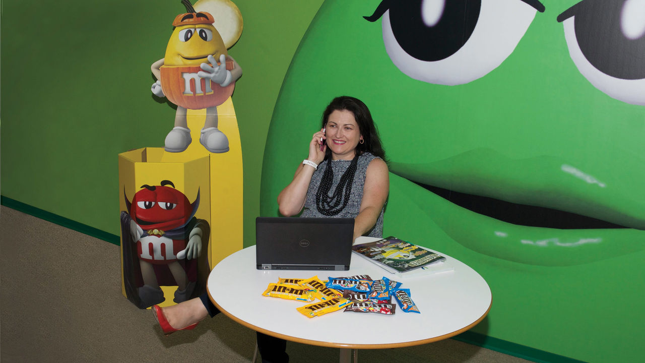 A woman sitting at a table in front of a green m&m's.