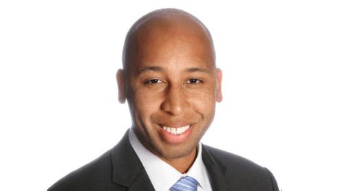 A man in a suit and tie smiling for the camera.