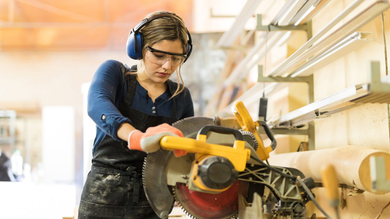 A woman working with a circular saw in a workshop.