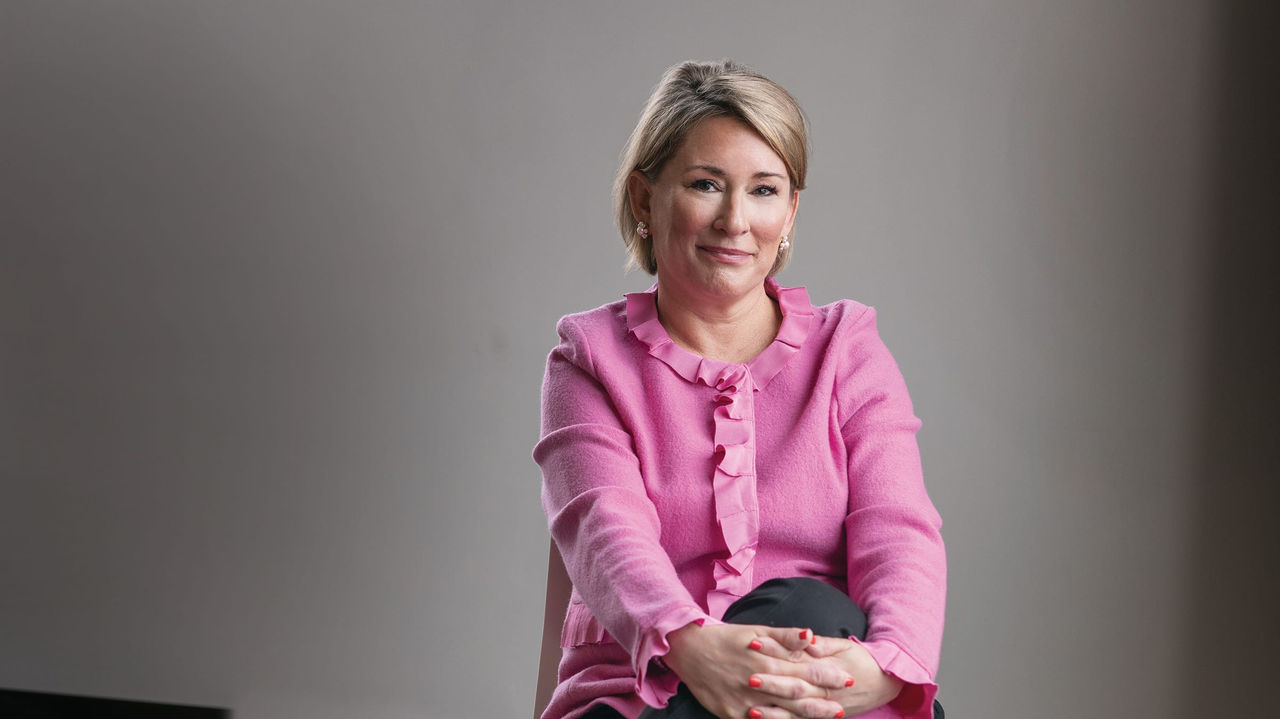 A woman in a pink shirt sitting on a chair.