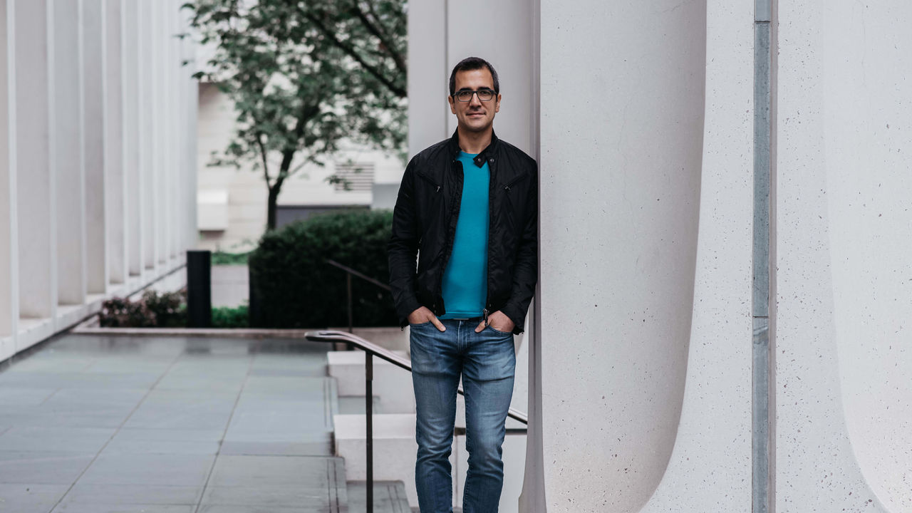 A man leaning against a column in front of a building.