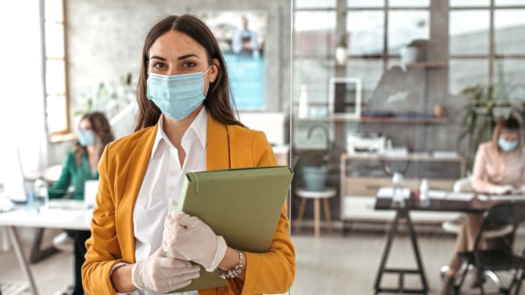 A woman wearing a surgical mask in an office.