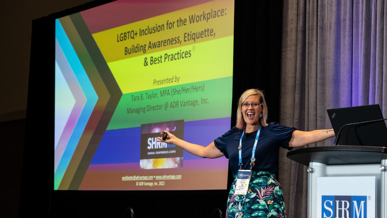 A woman standing in front of a screen giving a presentation.