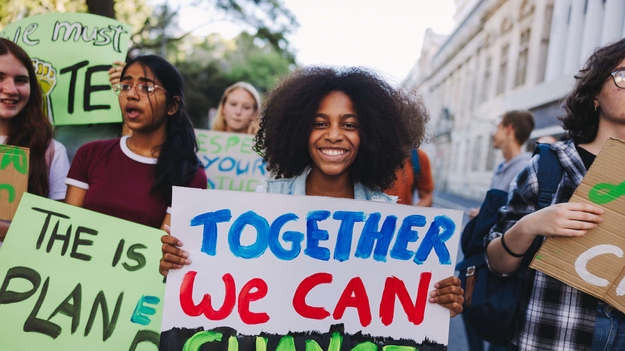 A group of young people holding signs that say together we can change.
