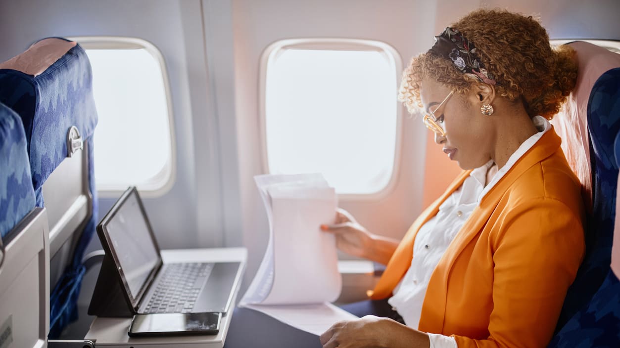 A woman sitting on an airplane with a laptop.