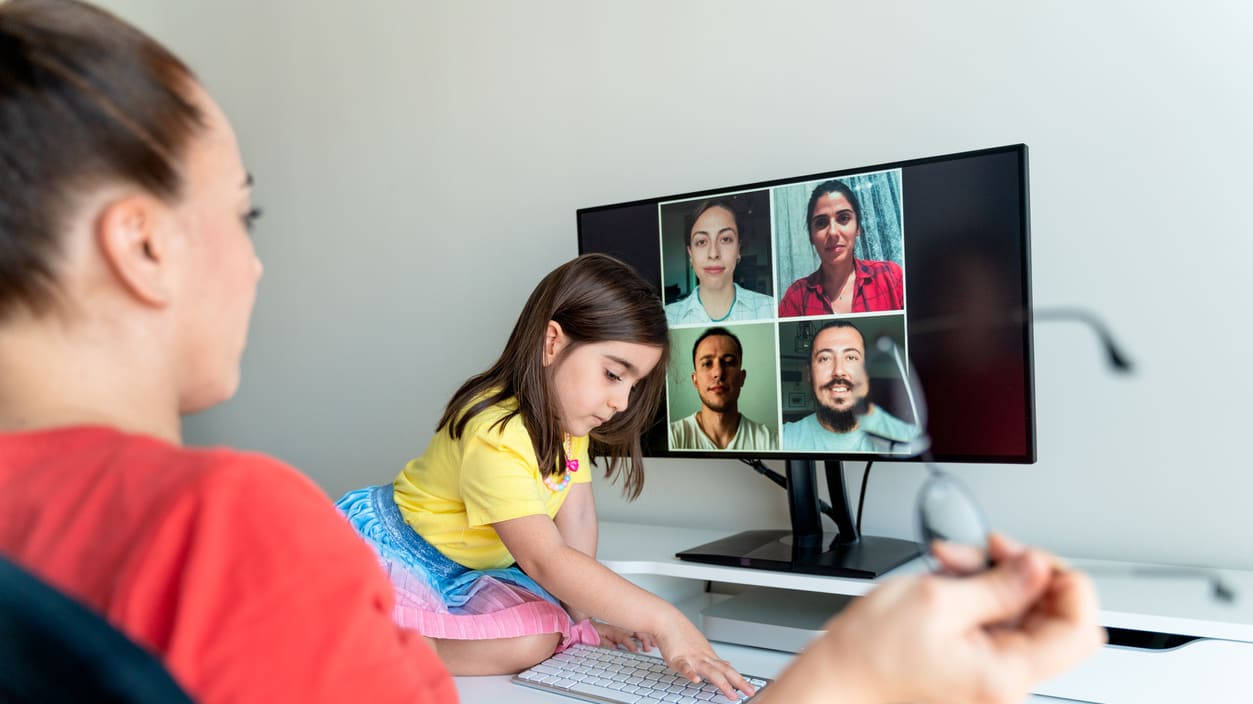 A woman and a little girl are using a video call on a computer.