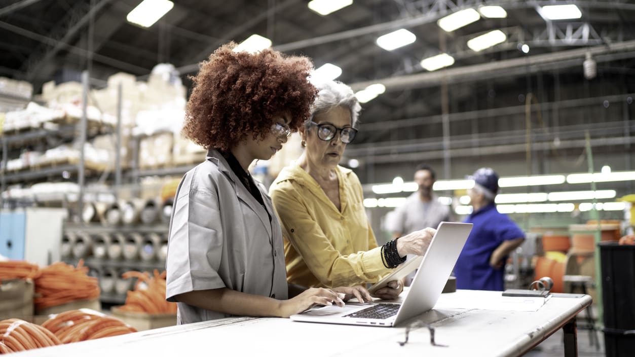 Two women looking at a laptop in a warehouse.