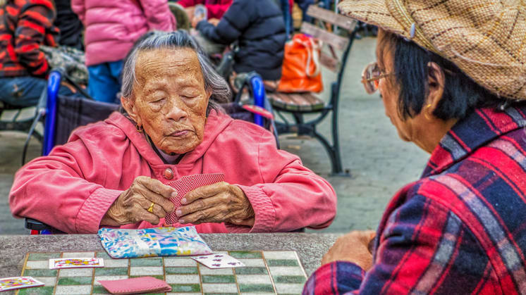 Two elderly women playing a game of checkers.
