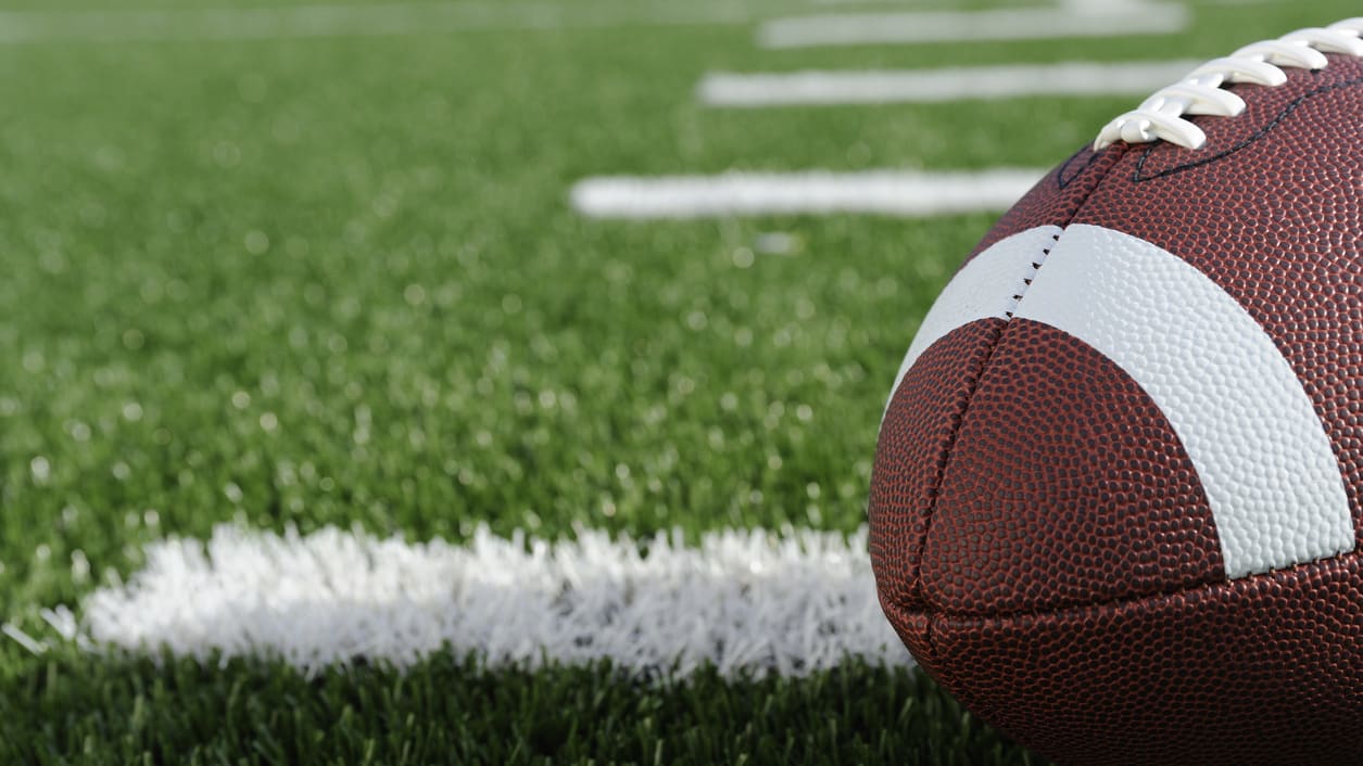 A football is sitting on a green field.
