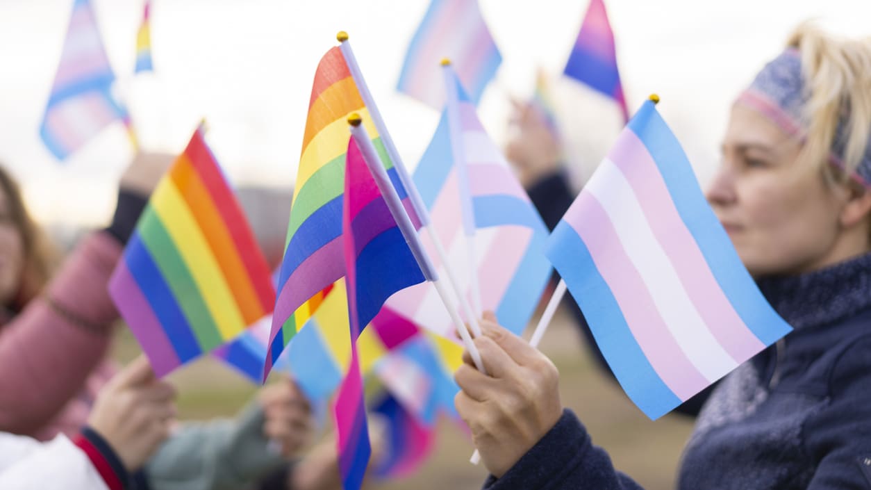 A group of people waving rainbow flags.