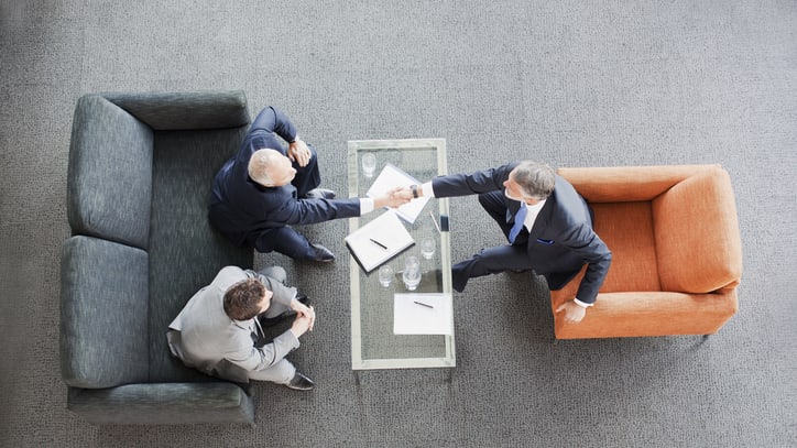 Three businessmen shaking hands at a table.