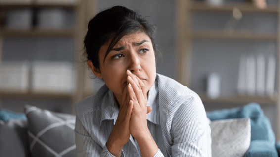 A woman sitting on a couch with her hand on her face.