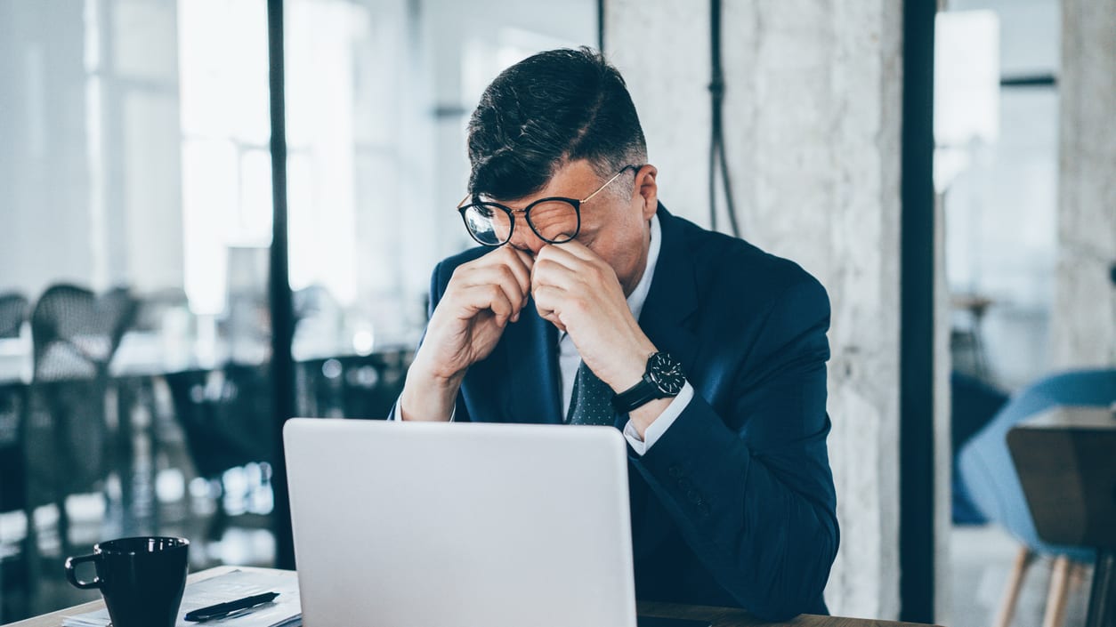 A man in a suit sitting at a table with a laptop.