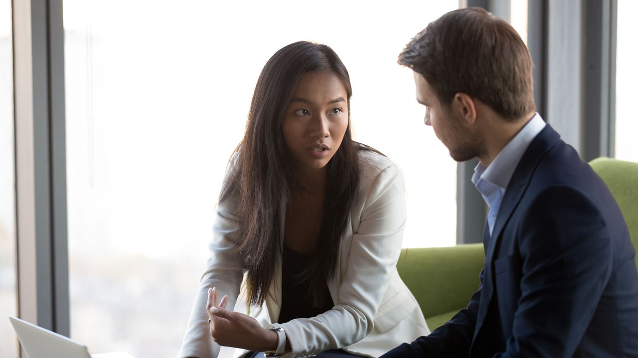 Two business people sitting at a table and talking to each other.