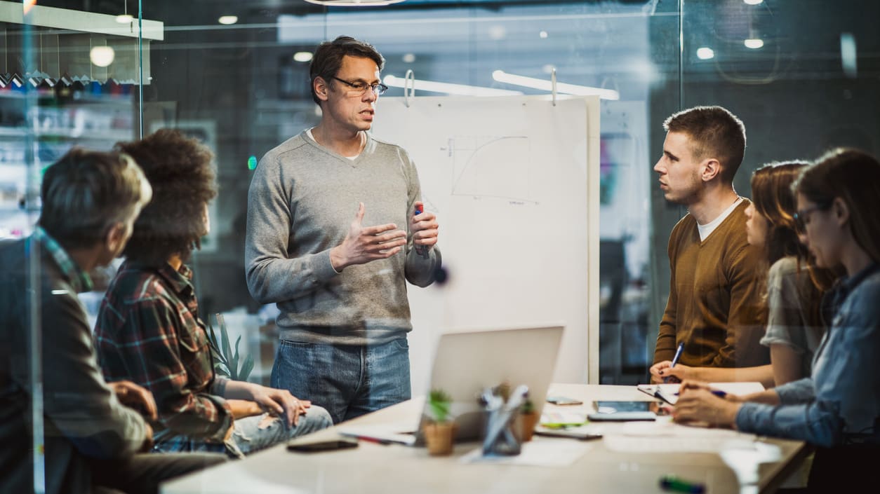 A group of people sitting around a table in a meeting room.